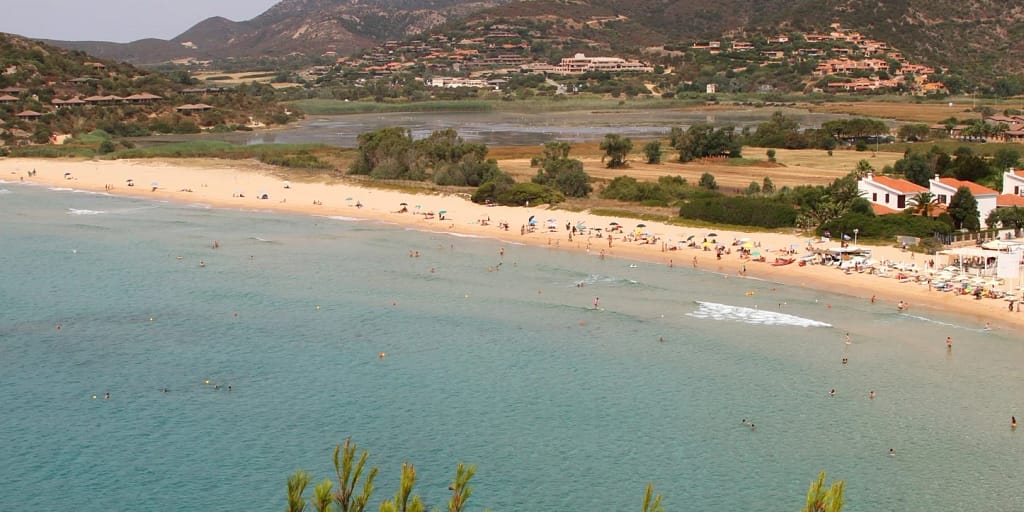 Resort Sardegna in vendita: una lunga spiaggia dorata su un mare basso e limpido, immagine della destinazione