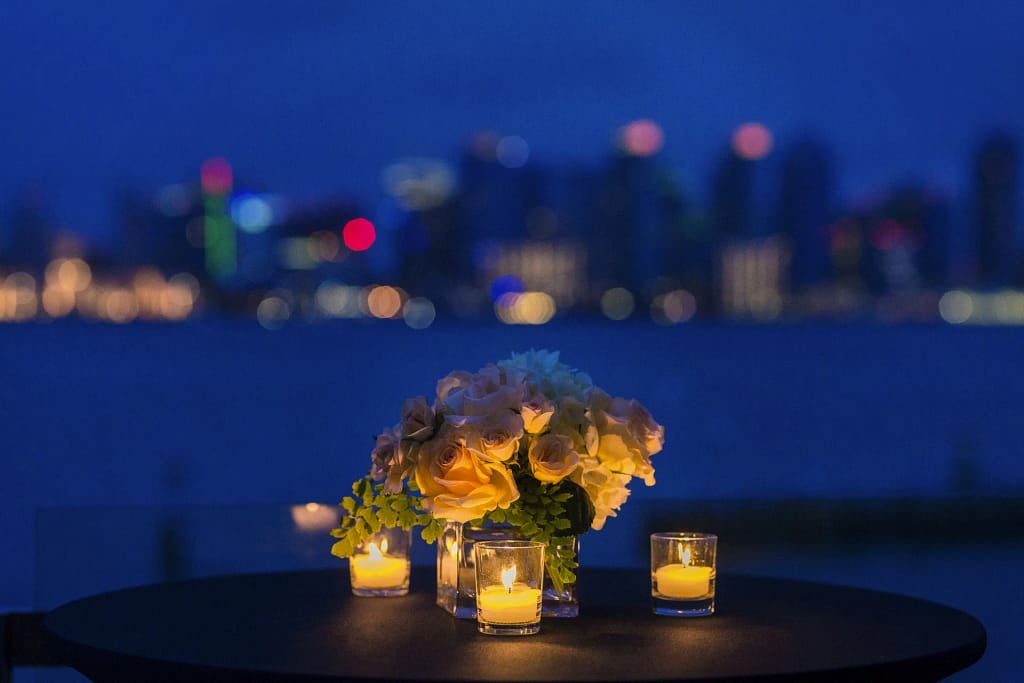 Eventi privati in villa: tavola di gala con fiori e candele davanti alla città di notte (foto illustrativa)
