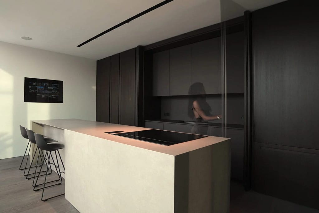 Materiali Interni di Lusso per Ville — The Villa Edit 15 Cucina con isola chiara e boiserie in legno scuro, progetto dello studio Federico Cappellina