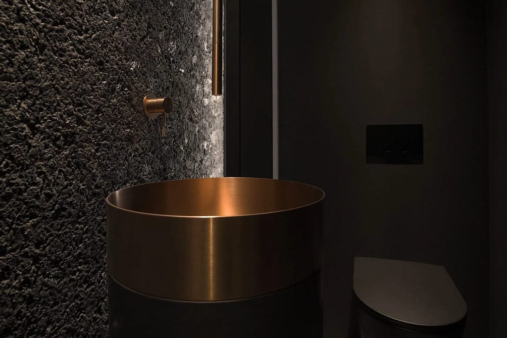 Pietra naturale: lavabo in rame su parete in pietra lavica