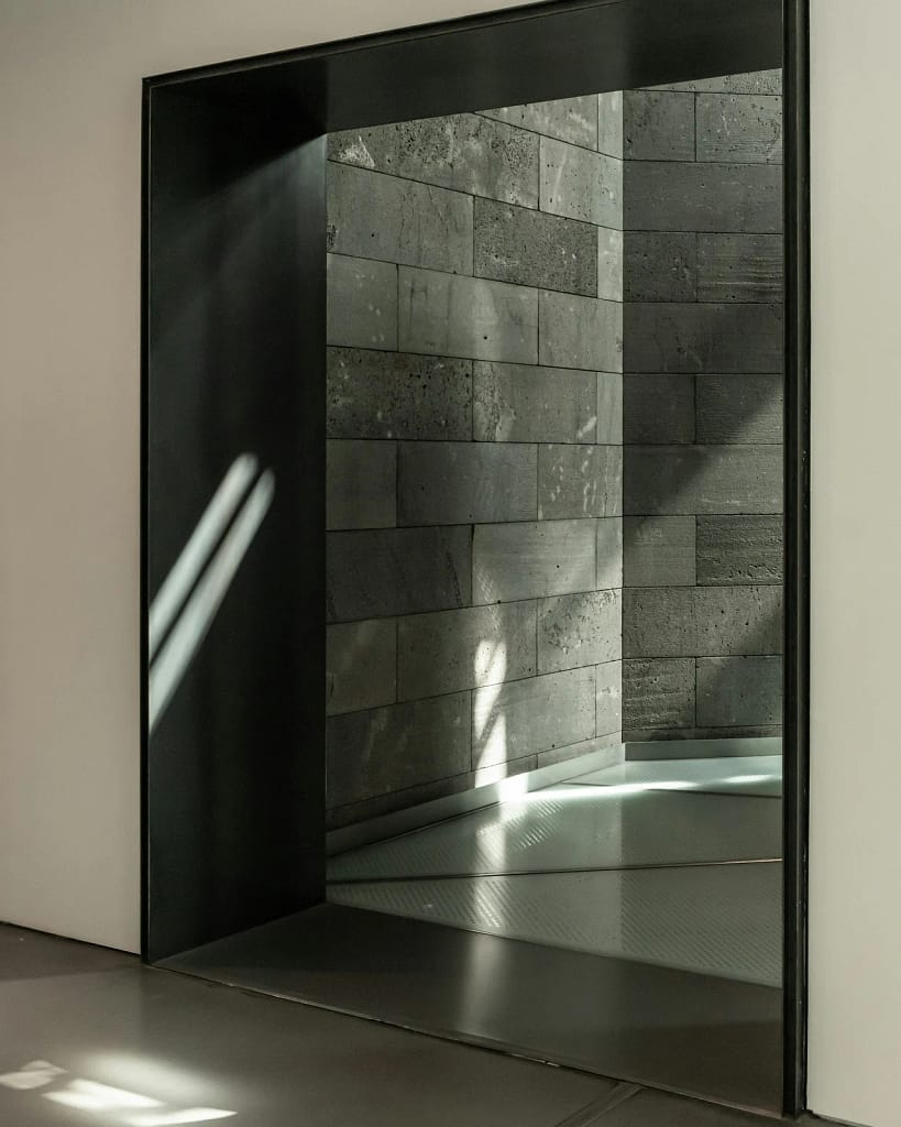 Serramenti di lusso — Porte e vetrate 14 Serramenti di lusso: grande porta d'ingresso a bilico con telaio nero e parete in pietra (foto illustrativa)