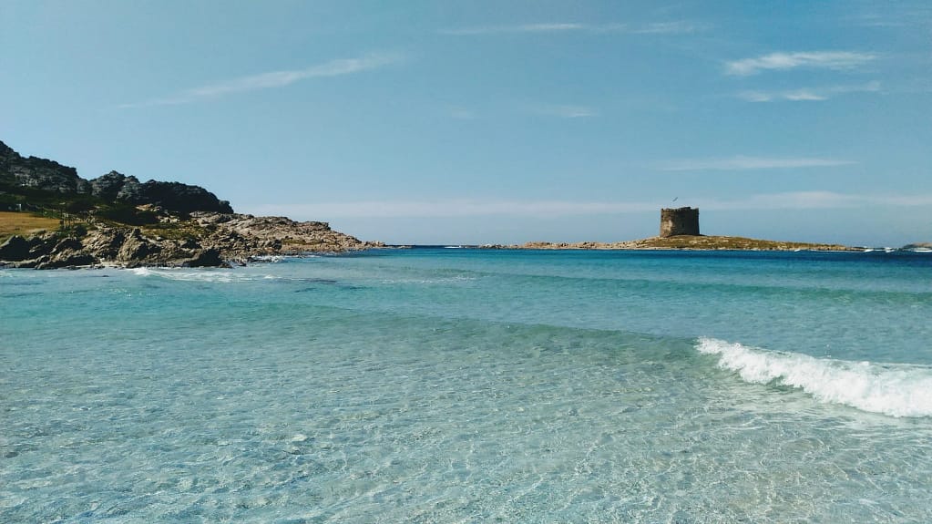 Resort Sardegna in vendita — Oltre 900 camere 7 Sardegna: la spiaggia della Pelosa con l'acqua trasparente e la torre sullo sfondo